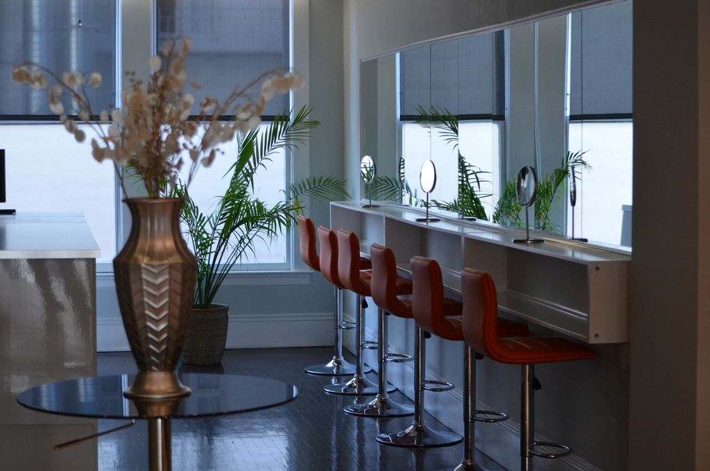 A bright salon styling area with mirror stations and bar stools