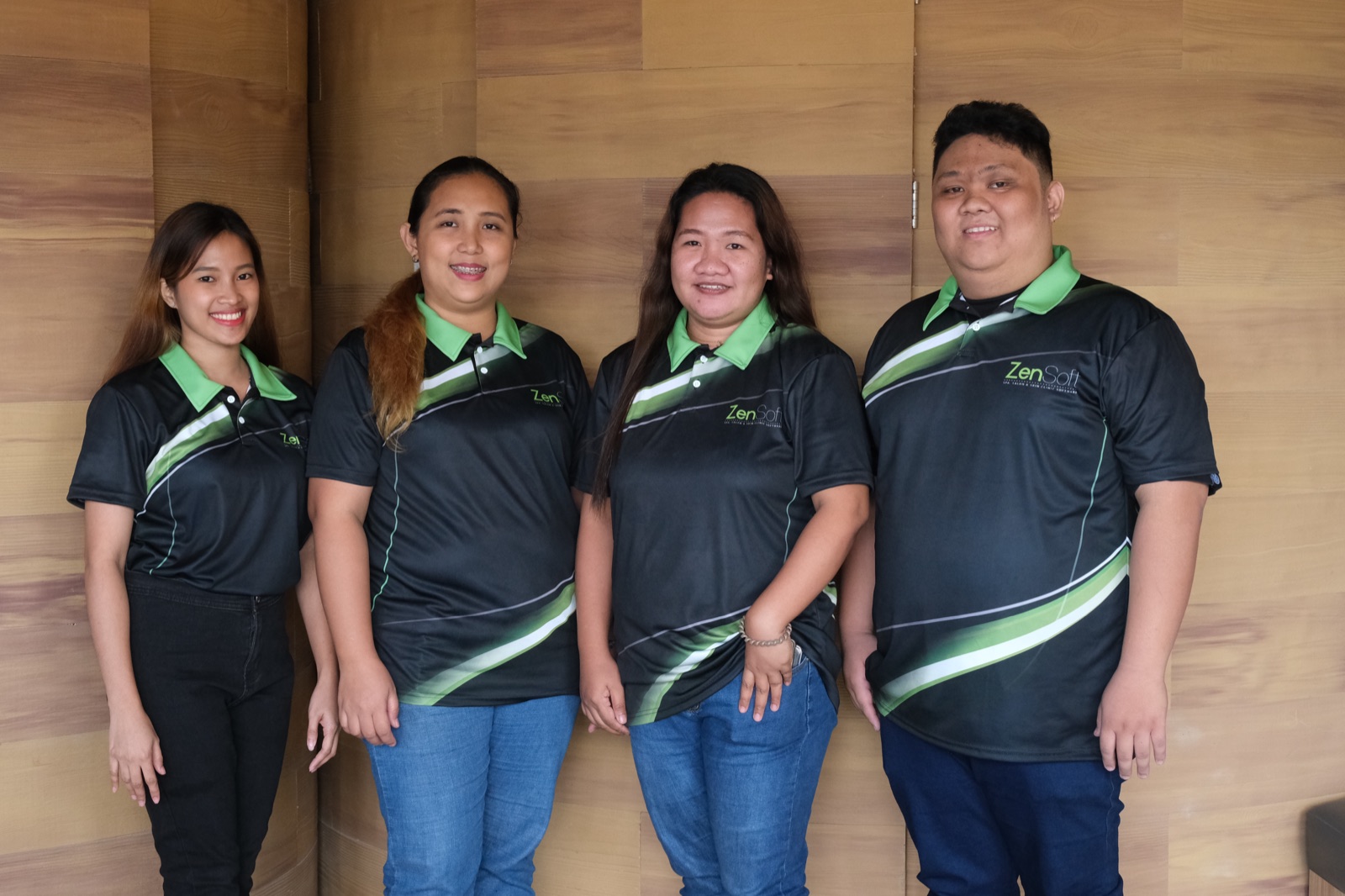 Four ZenSoft team members standing against the office wood panel wall